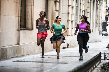 Group of friends running in city and chatting happily