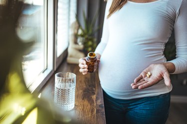 close view of a pregnant person taking prenatal vitamins that do not cause constipation